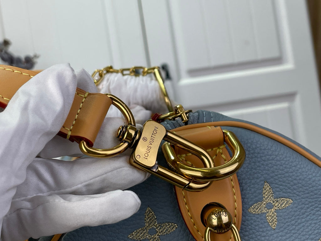 Louis Vuitton key ring and clasp hardware on tan strap attached to light blue monogram bag