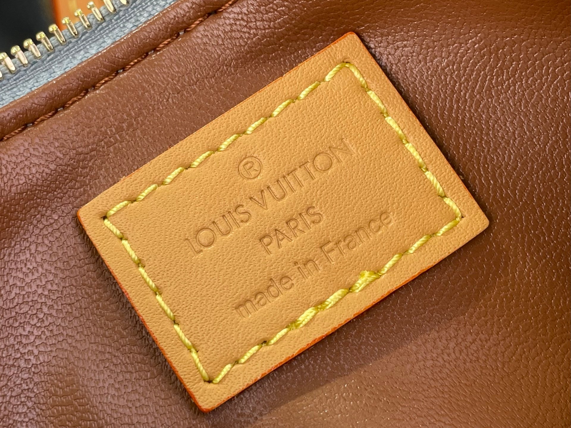 Louis Vuitton bag tan leather logo label with stitched edges and embossed “LOUIS VUITTON PARIS”