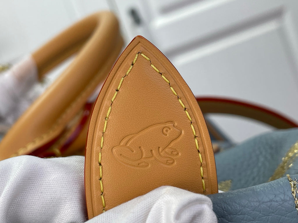 Louis Vuitton tan leather tag with embossed logo detail on light blue monogram bag