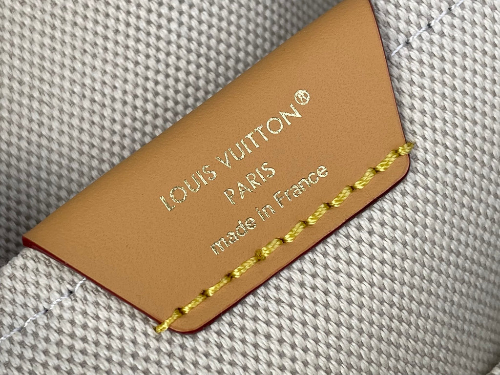 Louis Vuitton leather brand tag with gold lettering and braided trim