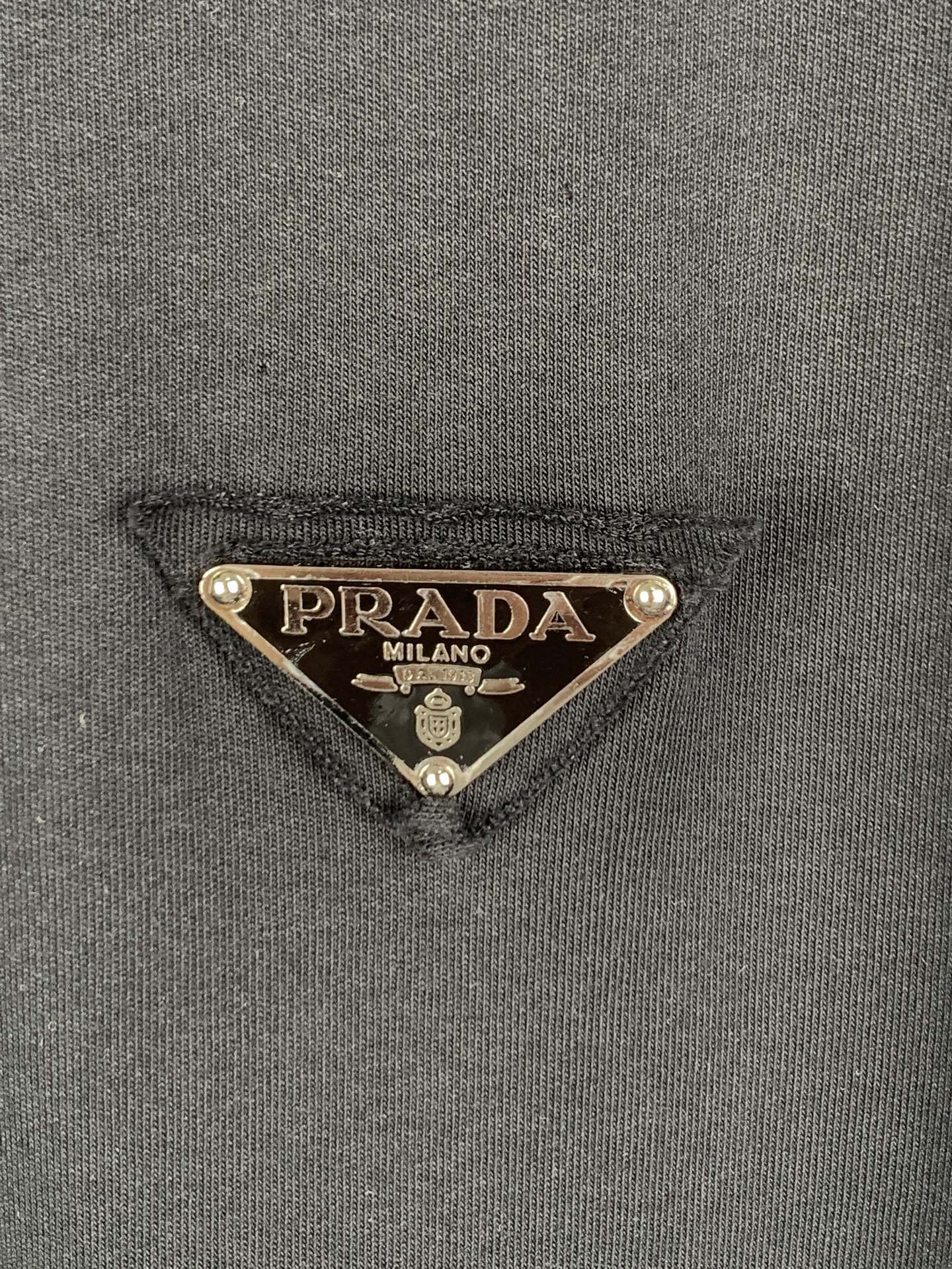 Prada triangle logo patch on dark T-shirt fabric