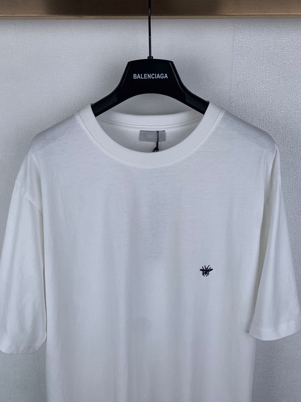 Dior short-sleeve T-shirt, close-up of white crew neck and small black chest emblem