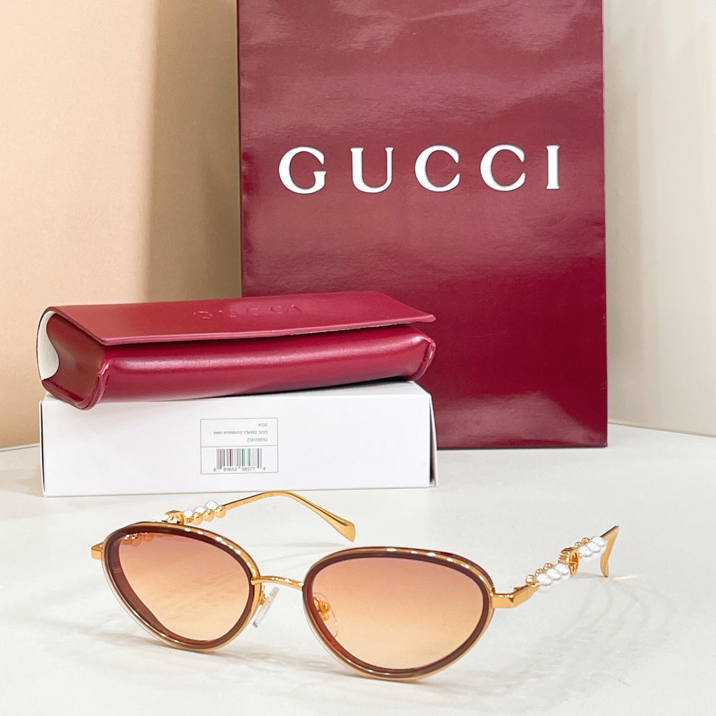 Gucci sunglasses with gold frame, amber lenses, oval shape and pearl-like temple details