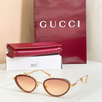 Gucci sunglasses with gold frame, amber lenses, oval shape and pearl-like temple details