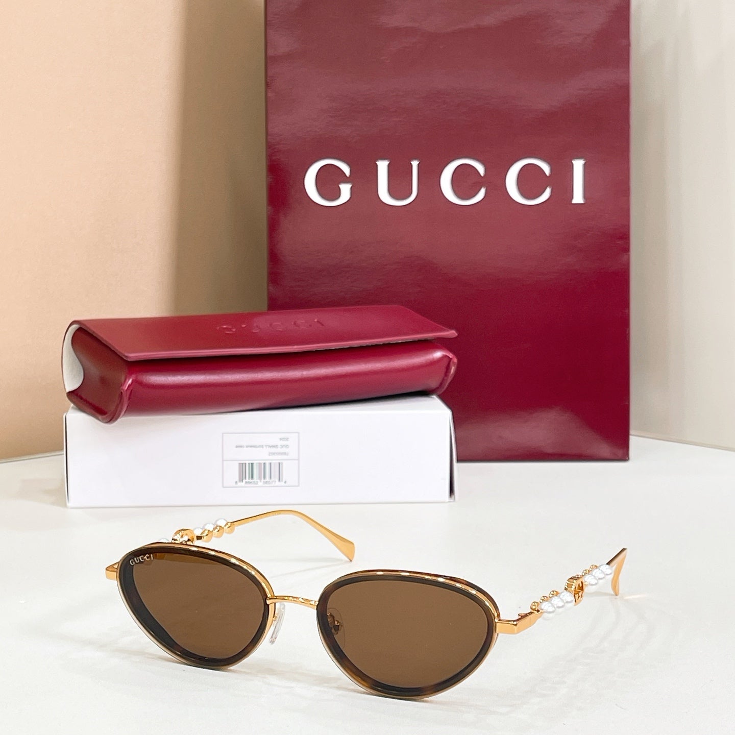 Gucci sunglasses with gold frame, dark brown lenses, oval shape and pearl-like accents