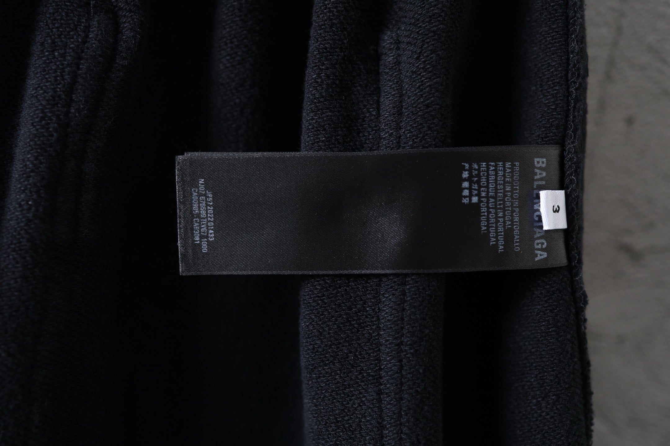 Dark fabric cargo pants with attached brand label tag on the waistband area
