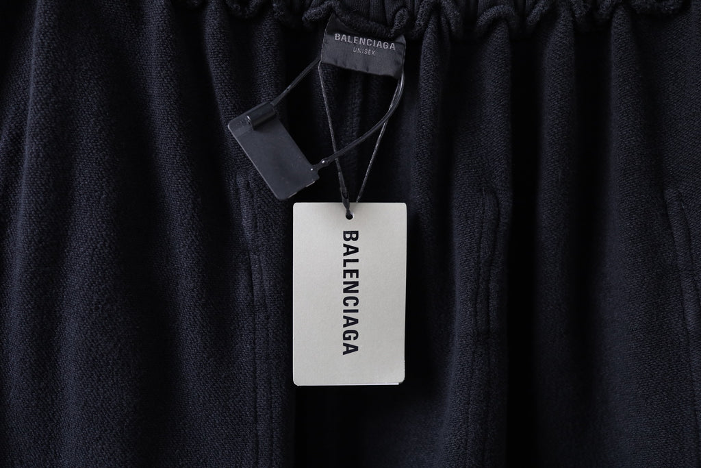 Dark cargo pants with branded hang tag on the waistband, elastic top edge