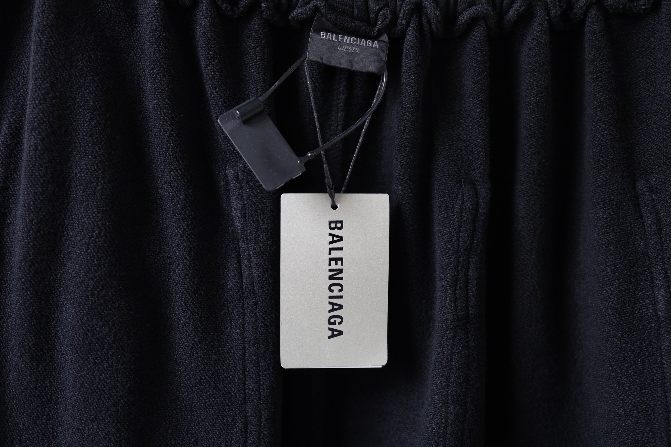Dark cargo pants with branded hang tag on the waistband, elastic top edge