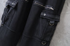 Close-up of dark cargo pants with flap pocket, snap button, and metal rings on strap