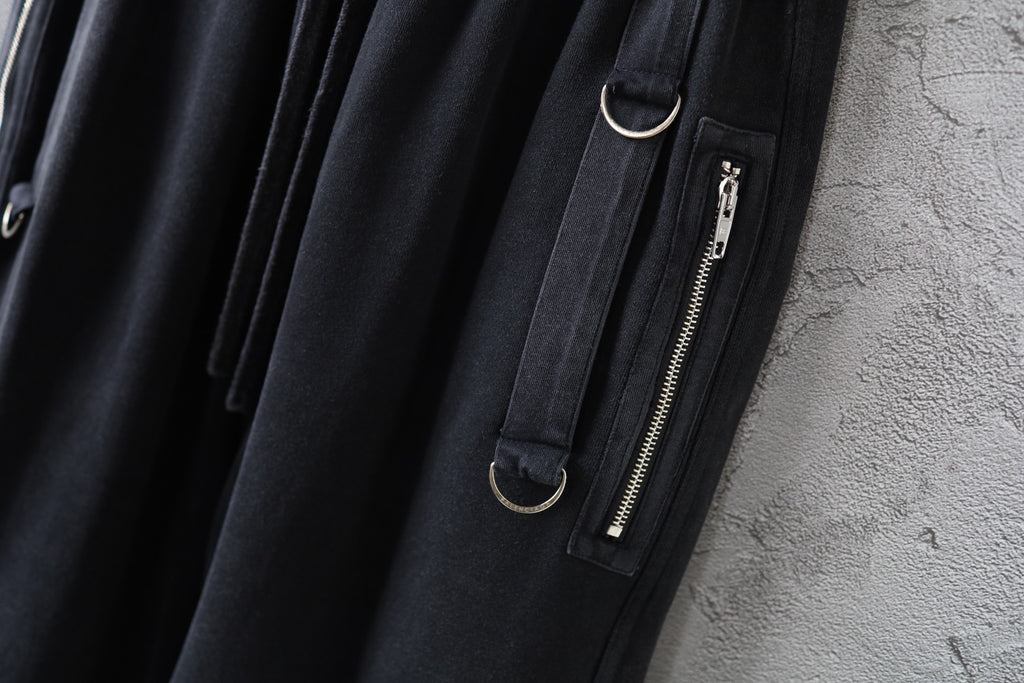 Dark cargo pants detail with zip pocket and metal zipper pull on the leg