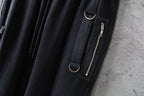 Dark cargo pants detail with zip pocket and metal zipper pull on the leg
