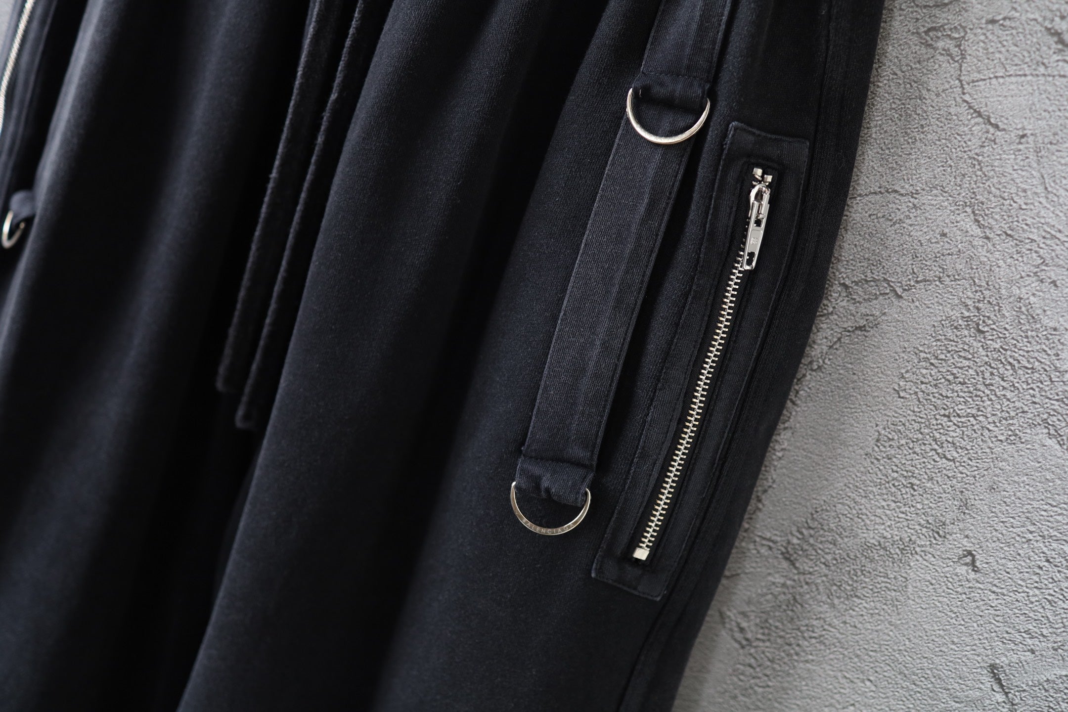 Dark cargo pants detail with zip pocket and metal zipper pull on the leg