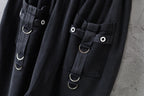 Close-up of dark cargo pants with flap pockets and metal ring straps with snap buttons