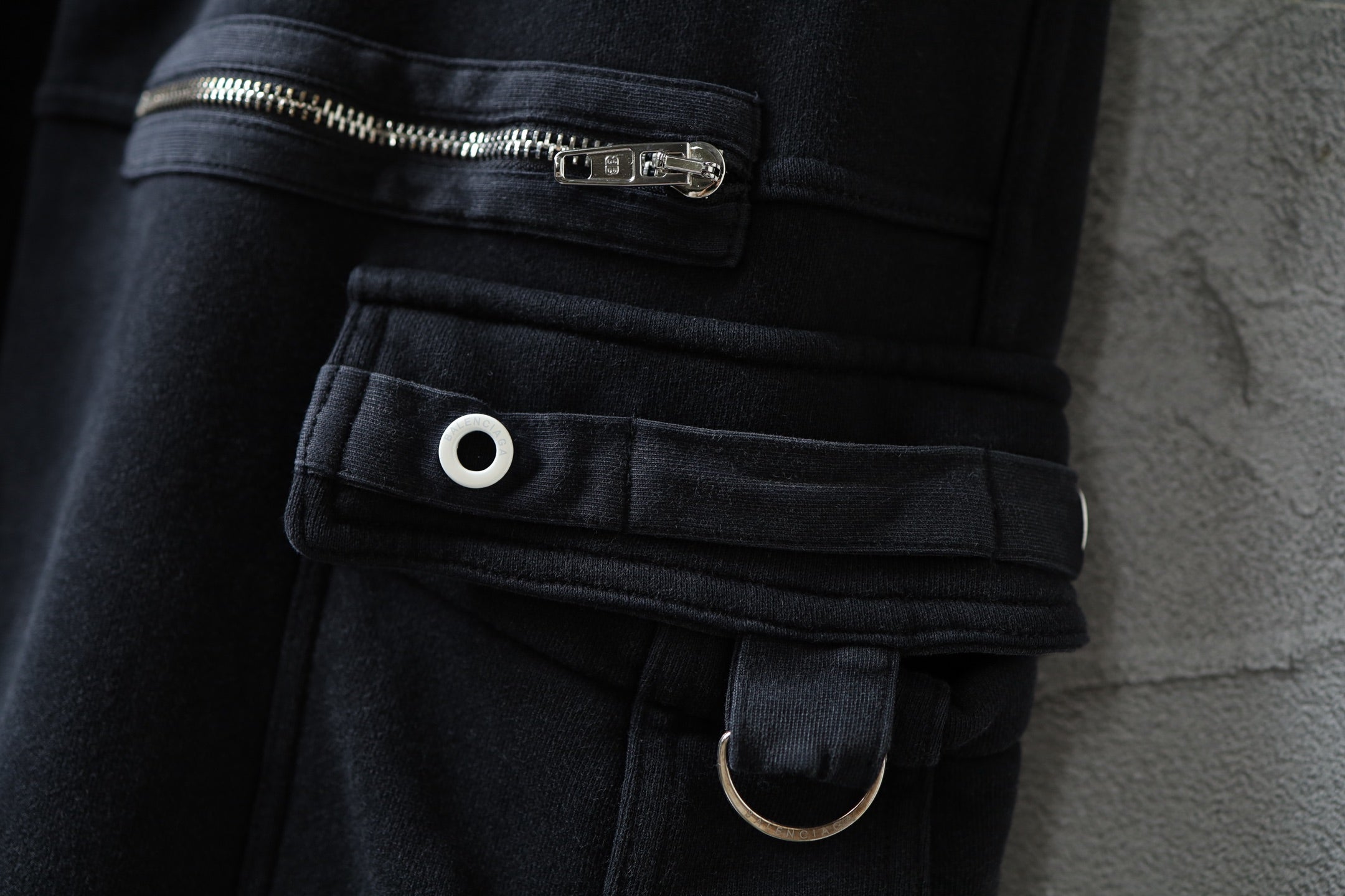 Dark cargo pants waist detail with elastic band, belt loop, snap button, and ring strap