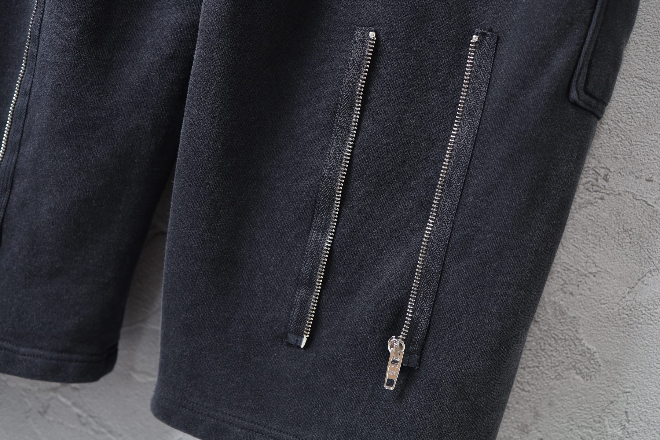Dark cargo pants with two vertical zip pockets on the leg and metal zipper pulls