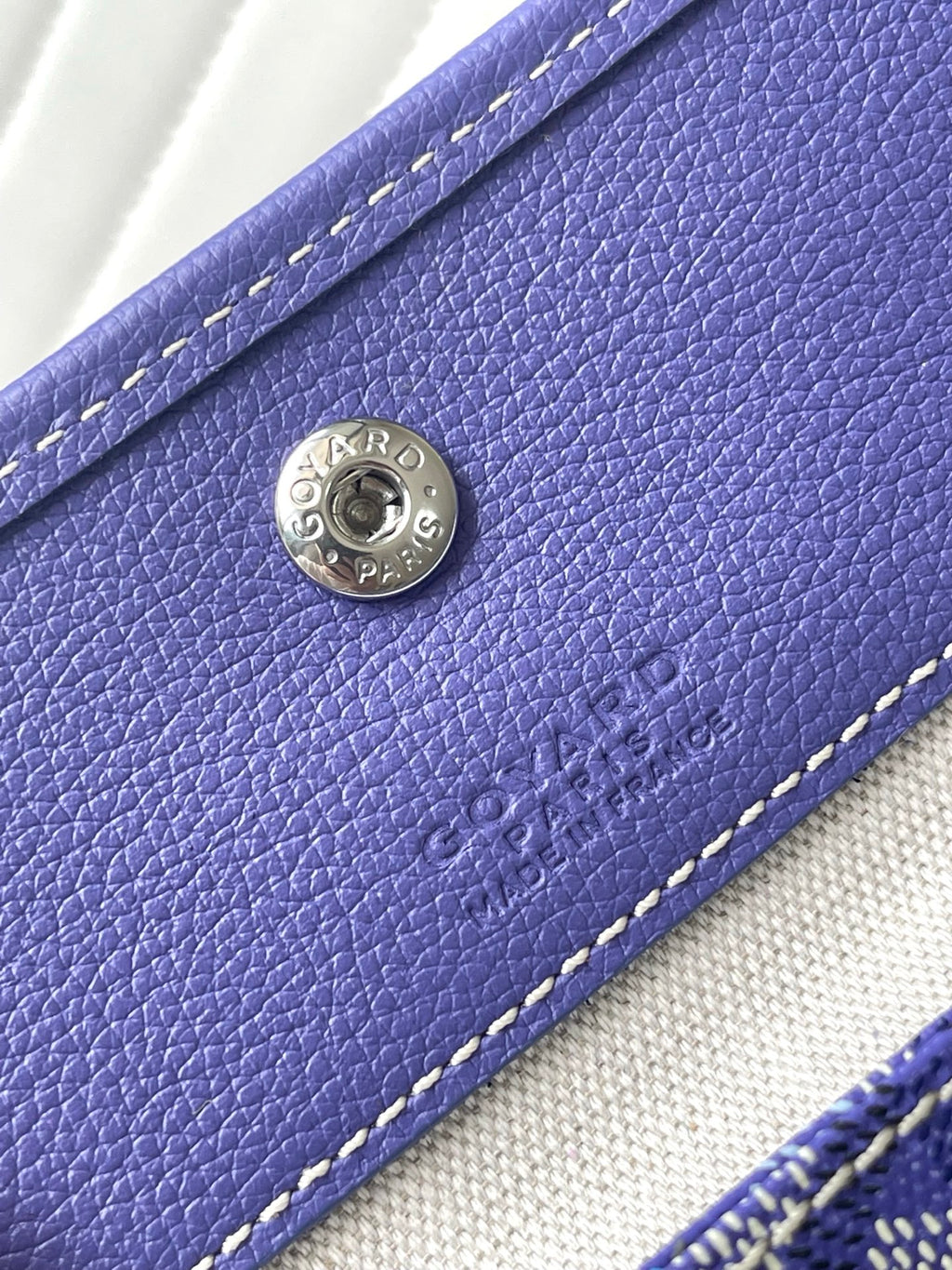 Purple leather front panel with round Goyard-style logo plate and stitching