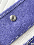 Purple leather front panel with round Goyard-style logo plate and stitching