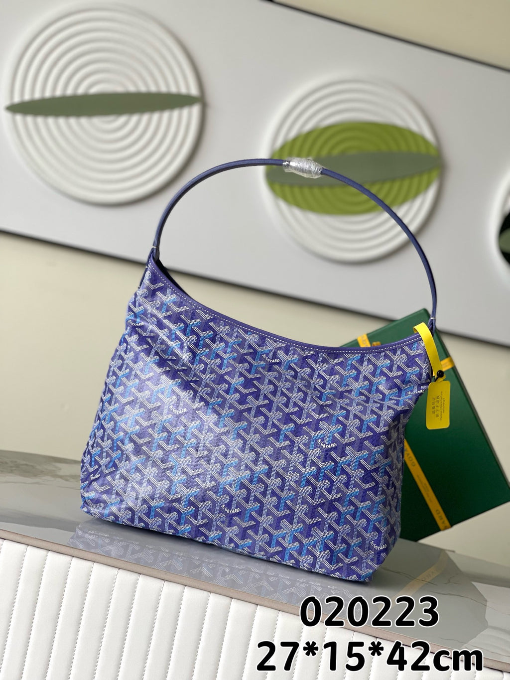 Purple Goyard-style hobo bag with allover pattern, curved top handle, and yellow tag