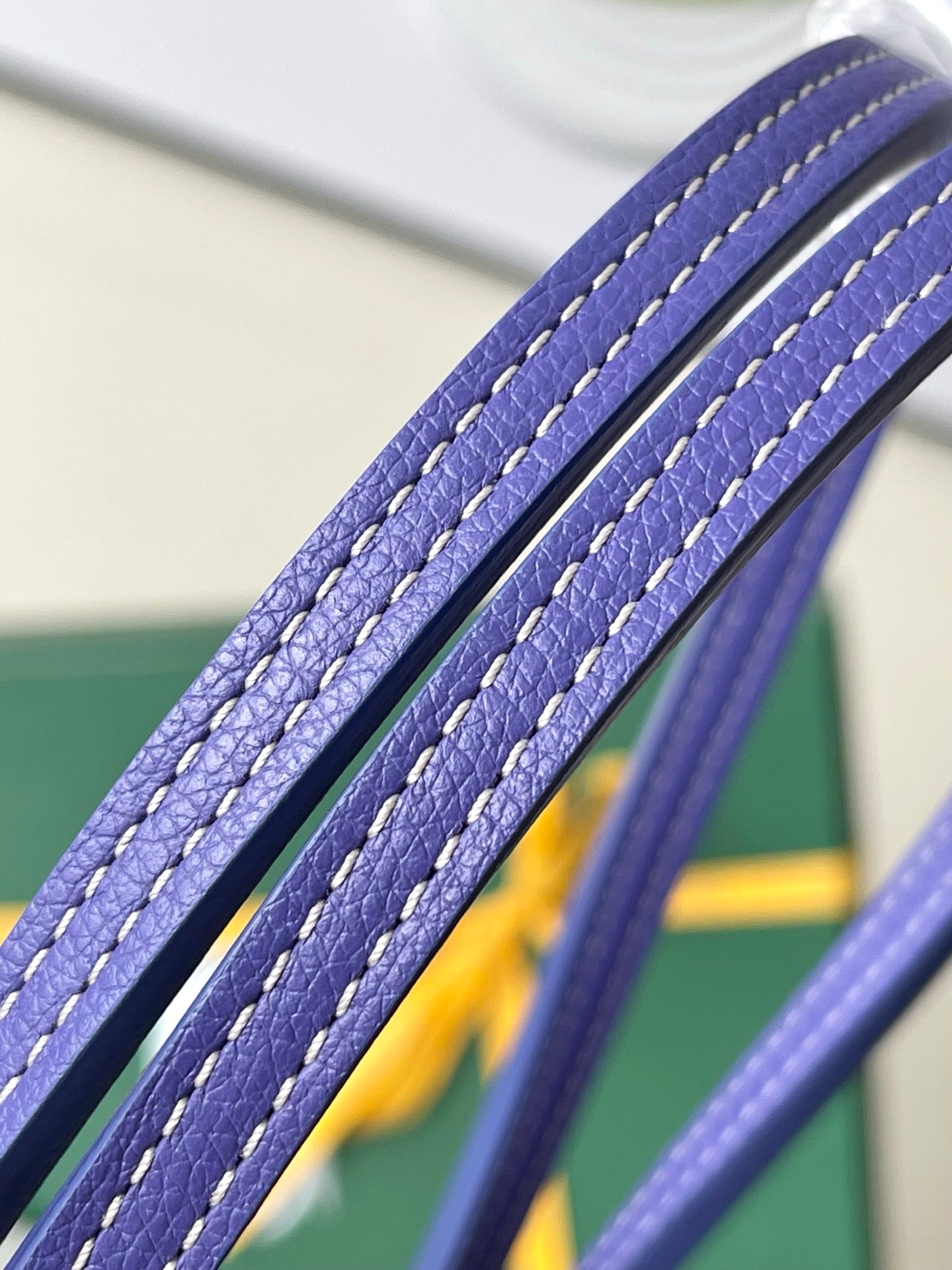 Blue leather-trim tote handle close-up with stitched edges and textured grain