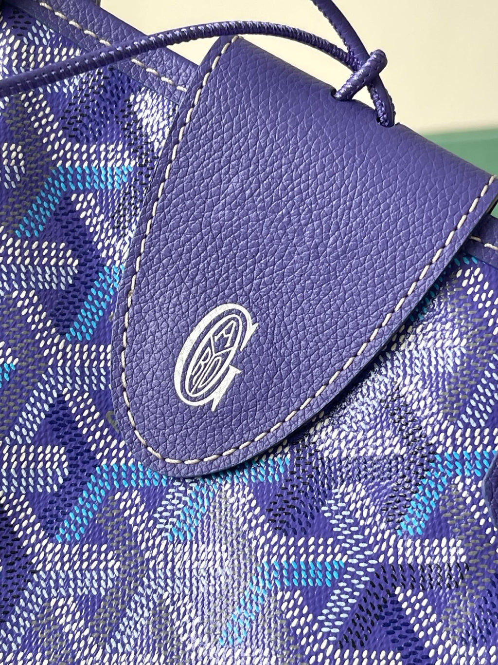 Blue patterned pouch with textured leather flap and circular logo emblem