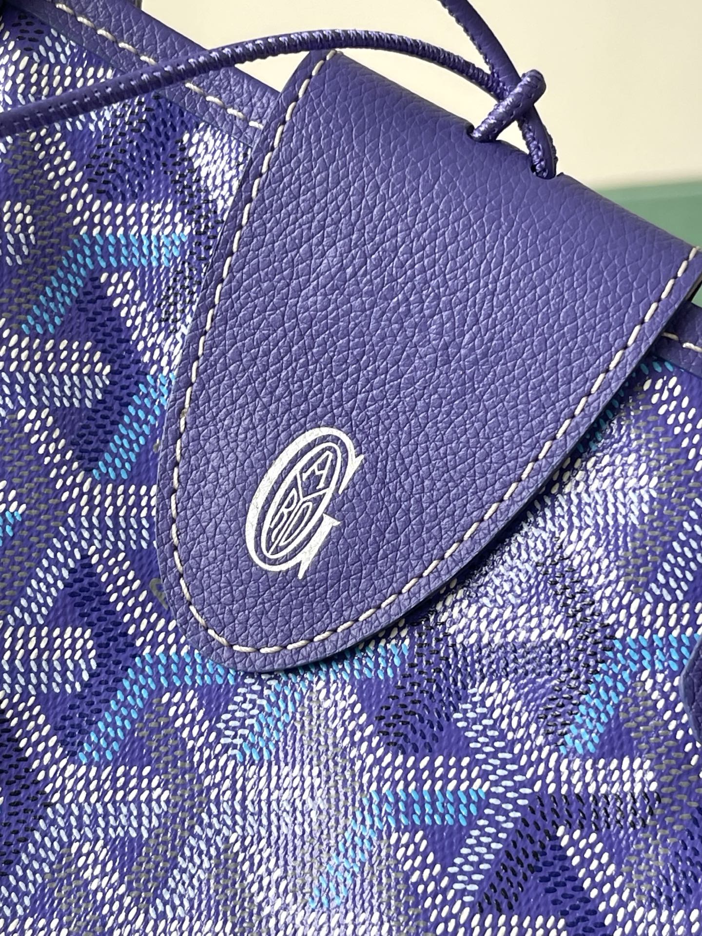 Blue patterned pouch with textured leather flap and circular logo emblem