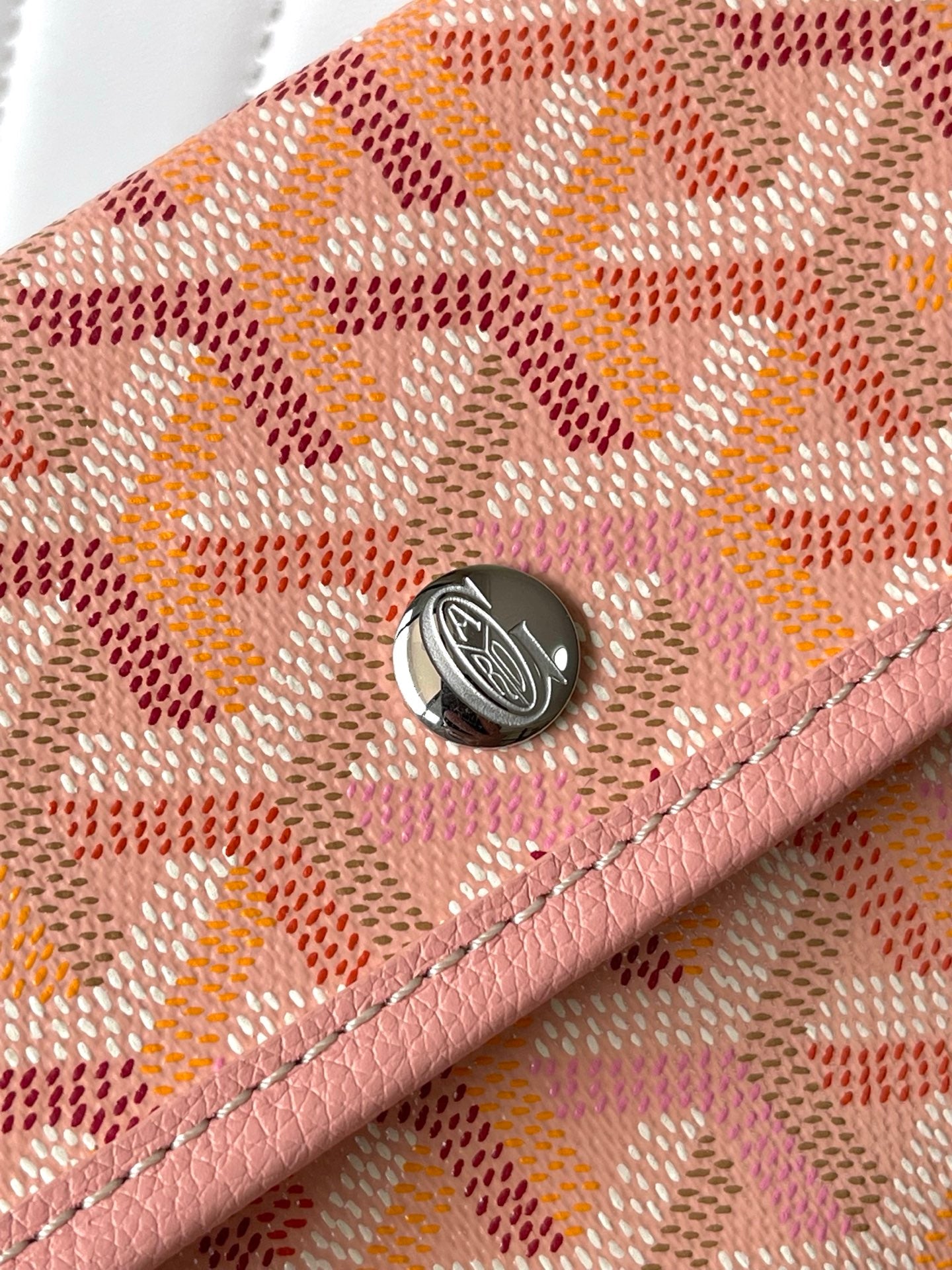 Pink patterned flap with metal snap and circular emblem detail