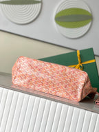 Pink Goyard patterned clutch pouch with zipper, shown on top of tote