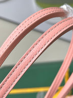 Pink leather tote handles with stitched seams on a patterned Goyard bag