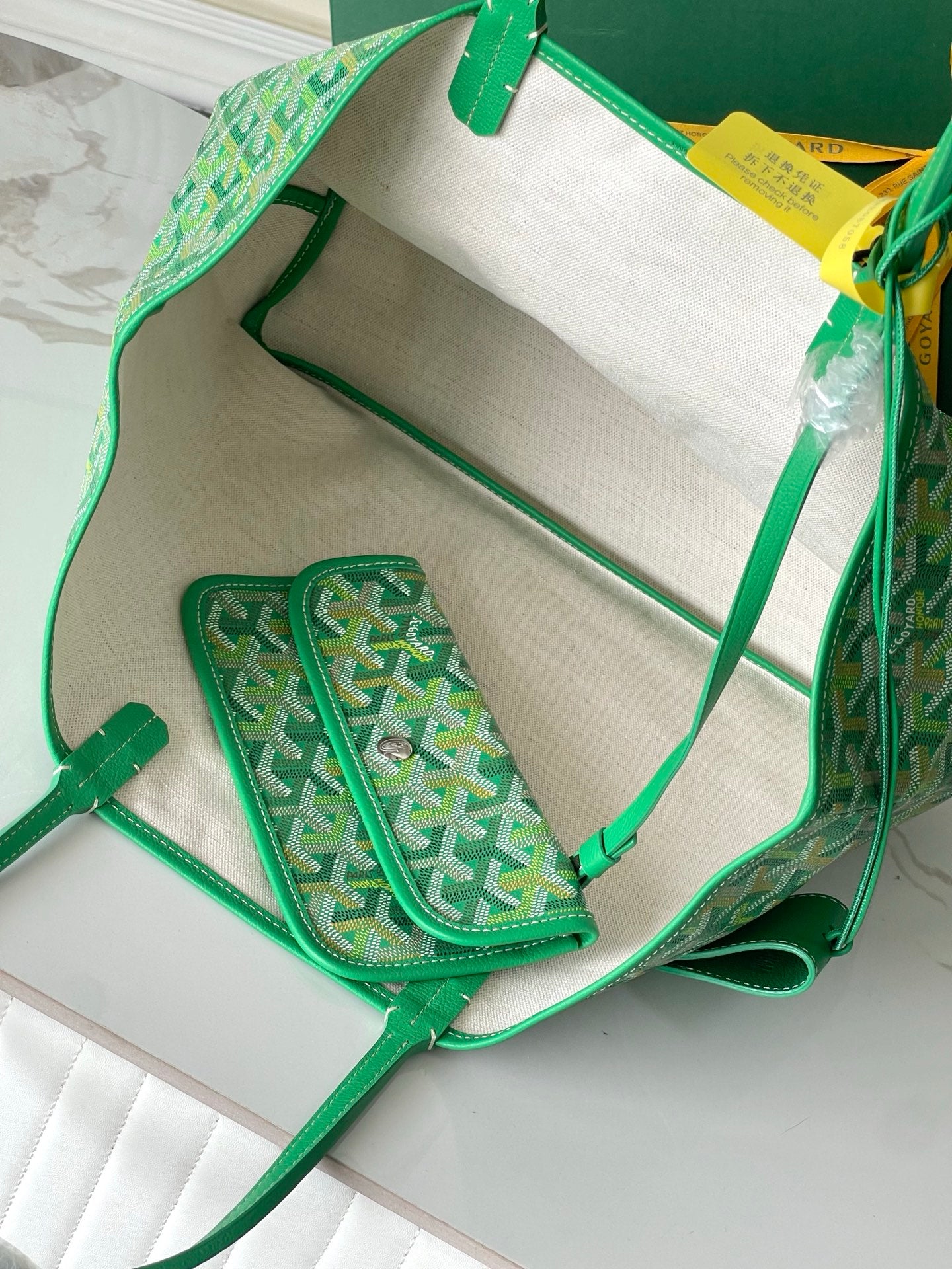 Open green tote bag showing white interior and small matching pocket pouch