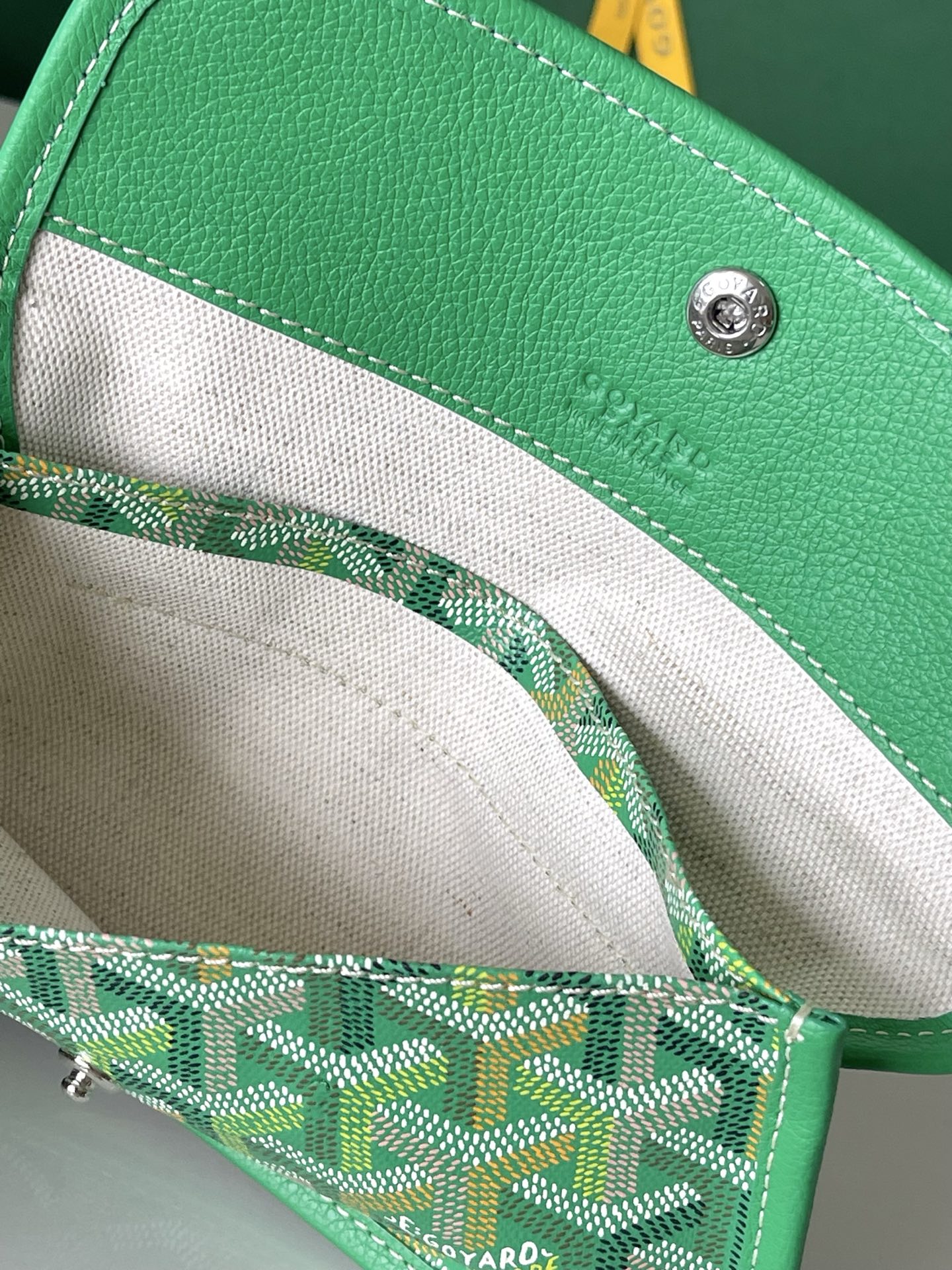 Open tote bag interior with green patterned pouch and stitched trim