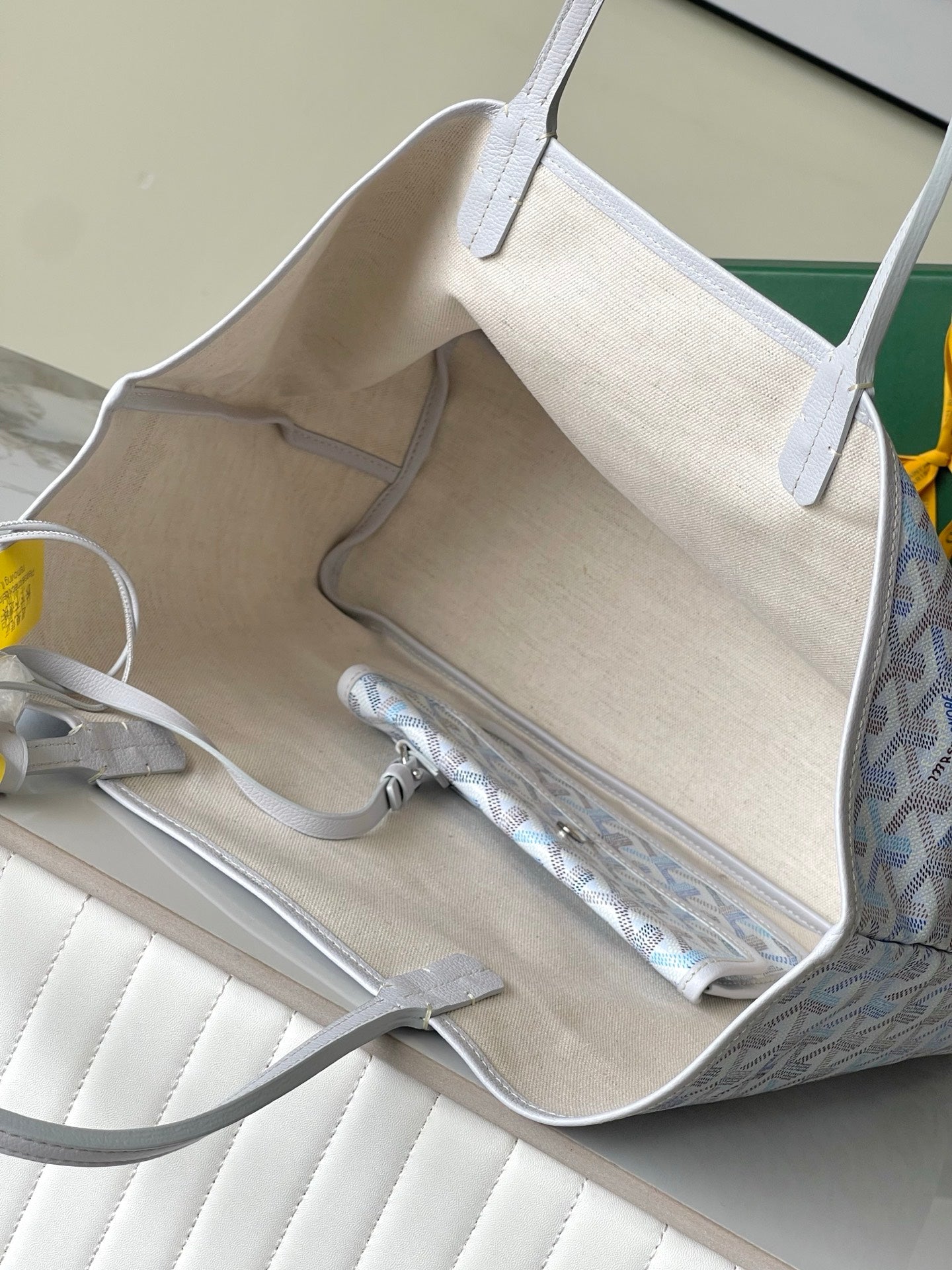 Opened interior of light blue patterned designer tote bag with beige lining and pockets