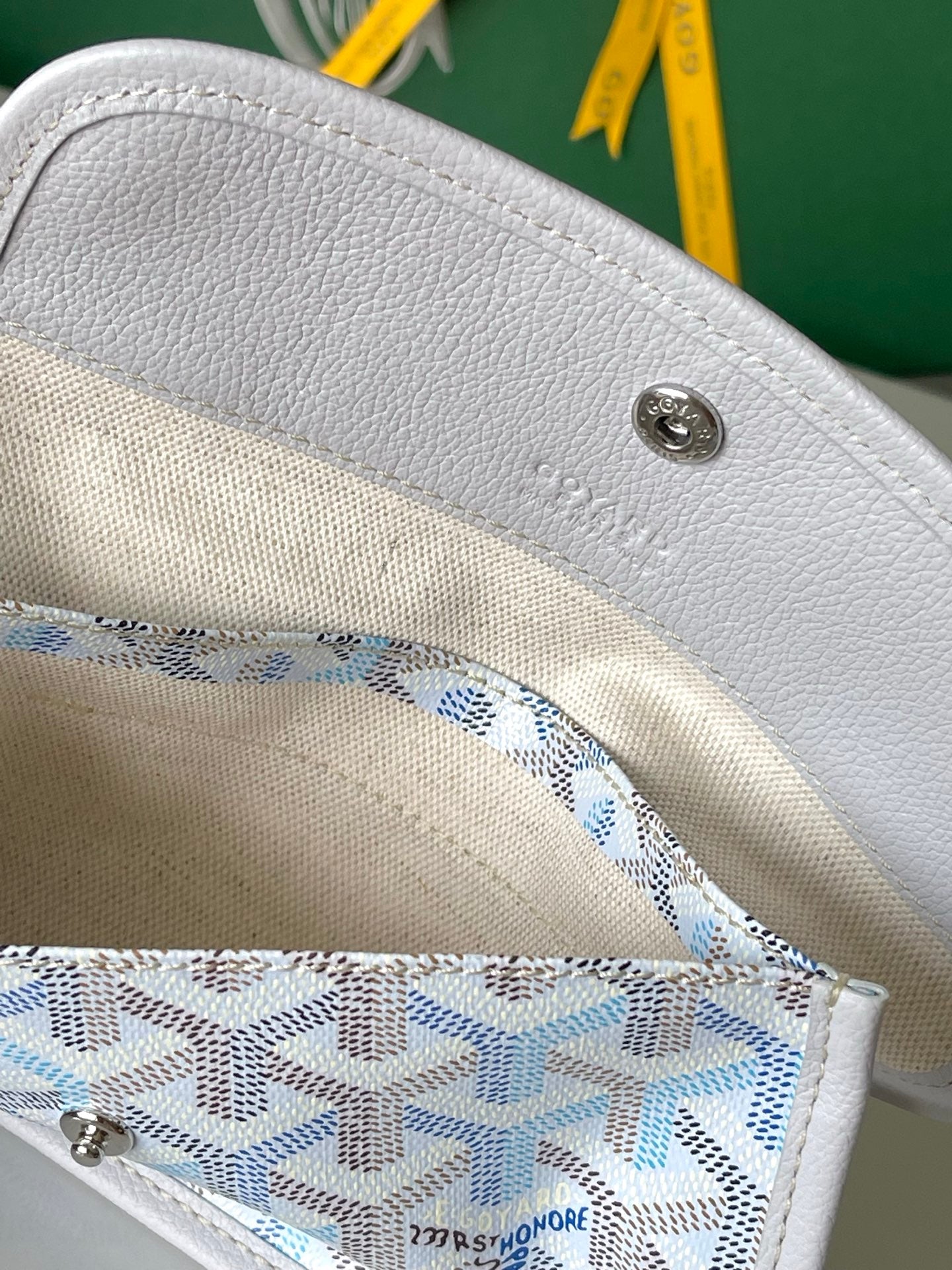 Light blue designer tote bag top with metal snap button and blue-and-white inner lining