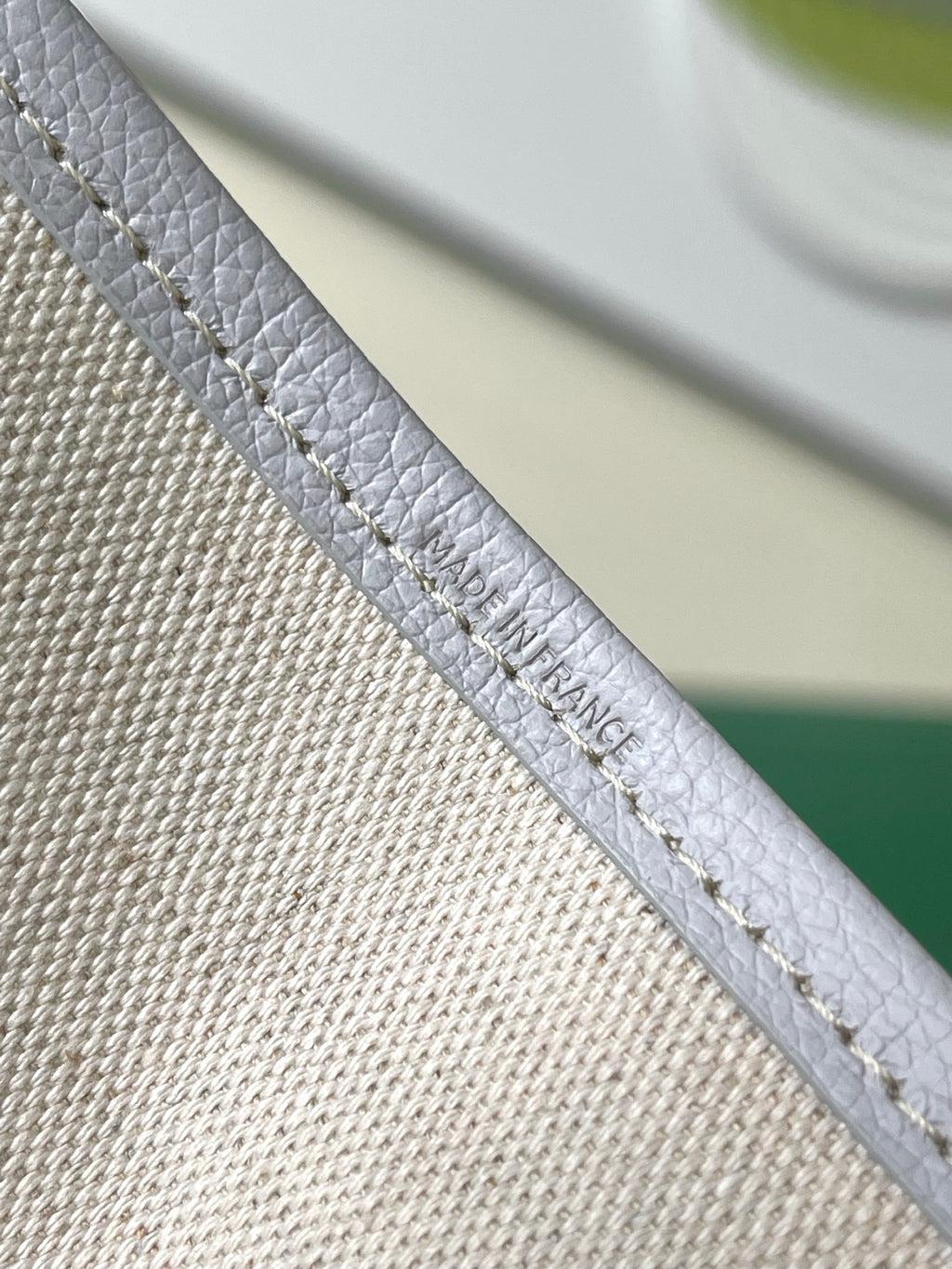 Close-up of light blue patterned tote bag strap with embossed text near edge