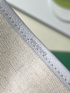 Close-up of light blue patterned tote bag strap with embossed text near edge