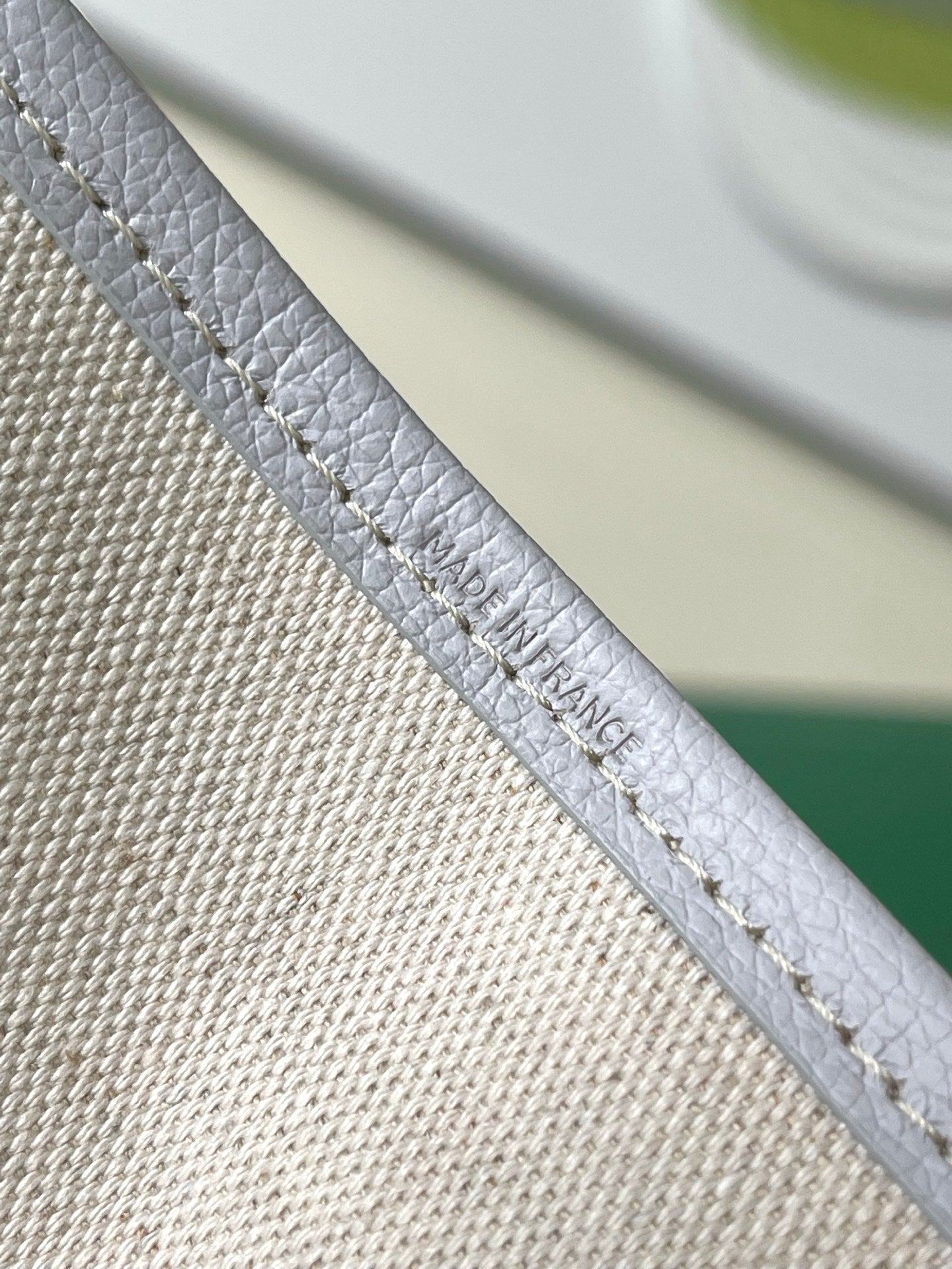 Close-up of light blue patterned tote bag strap with embossed text near edge