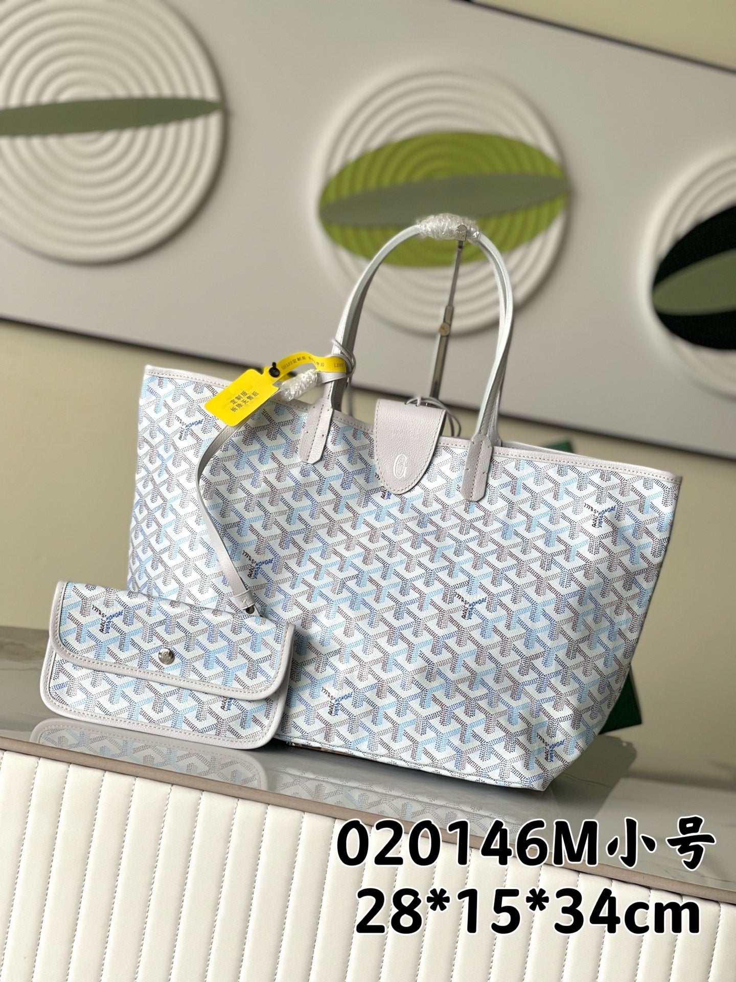 Light blue-and-white patterned designer tote bag with two top handles and small pouch