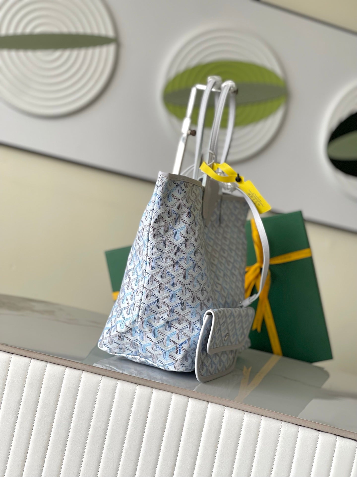 Light blue-and-white patterned designer tote bag shown from side with attached zip pouch