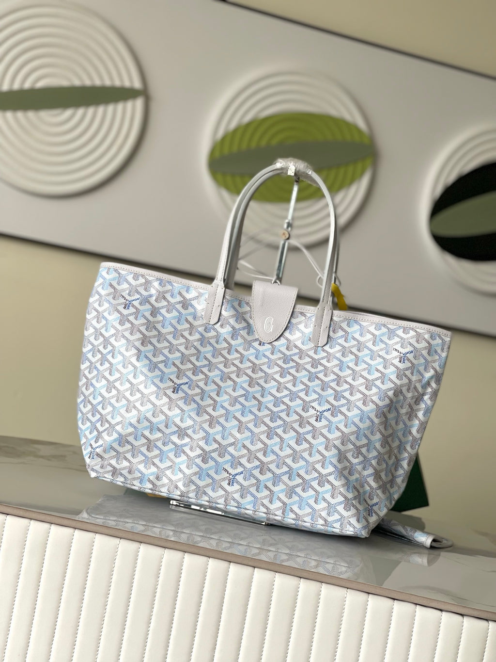 Light blue-and-white patterned designer tote bag with two top handles and snap detail