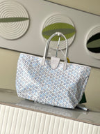 Light blue-and-white patterned designer tote bag with two top handles and snap detail