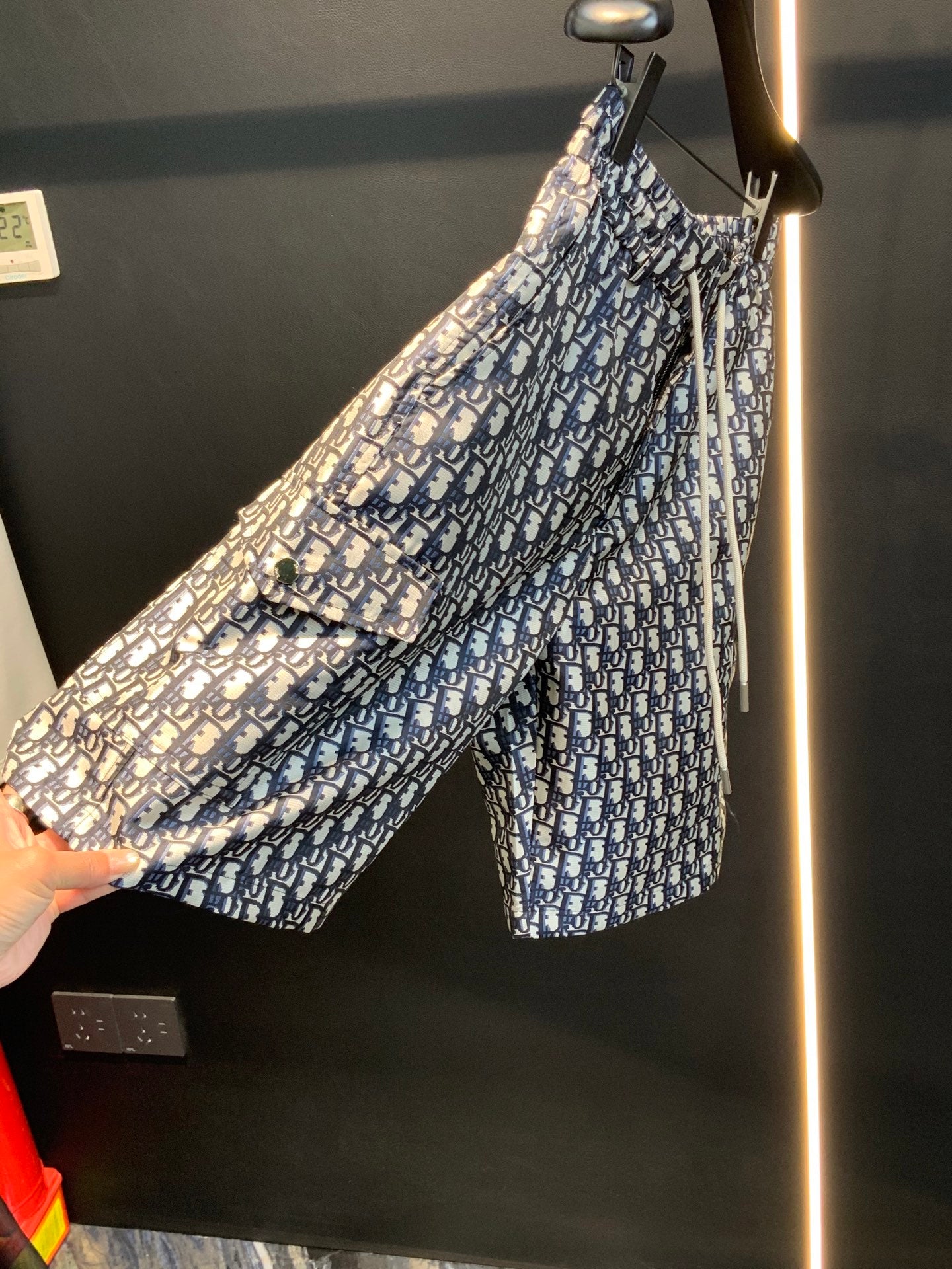 Dior monogram print shorts being held up, fabric detail, blue and cream