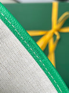 Green leather tote bag strap with contrast stitching and textured grain