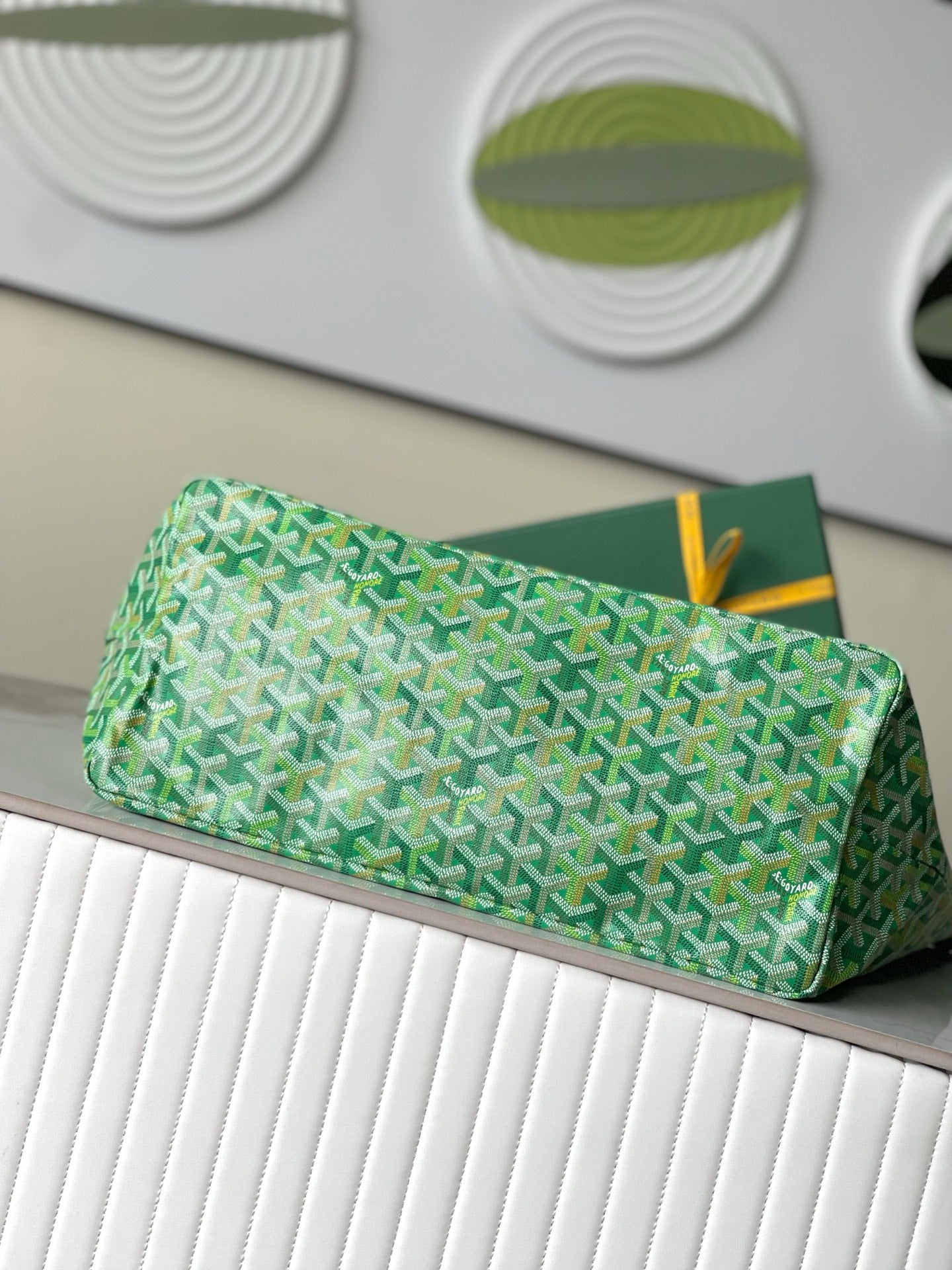 Green patterned pouch with fold-over top and yellow hanging tag