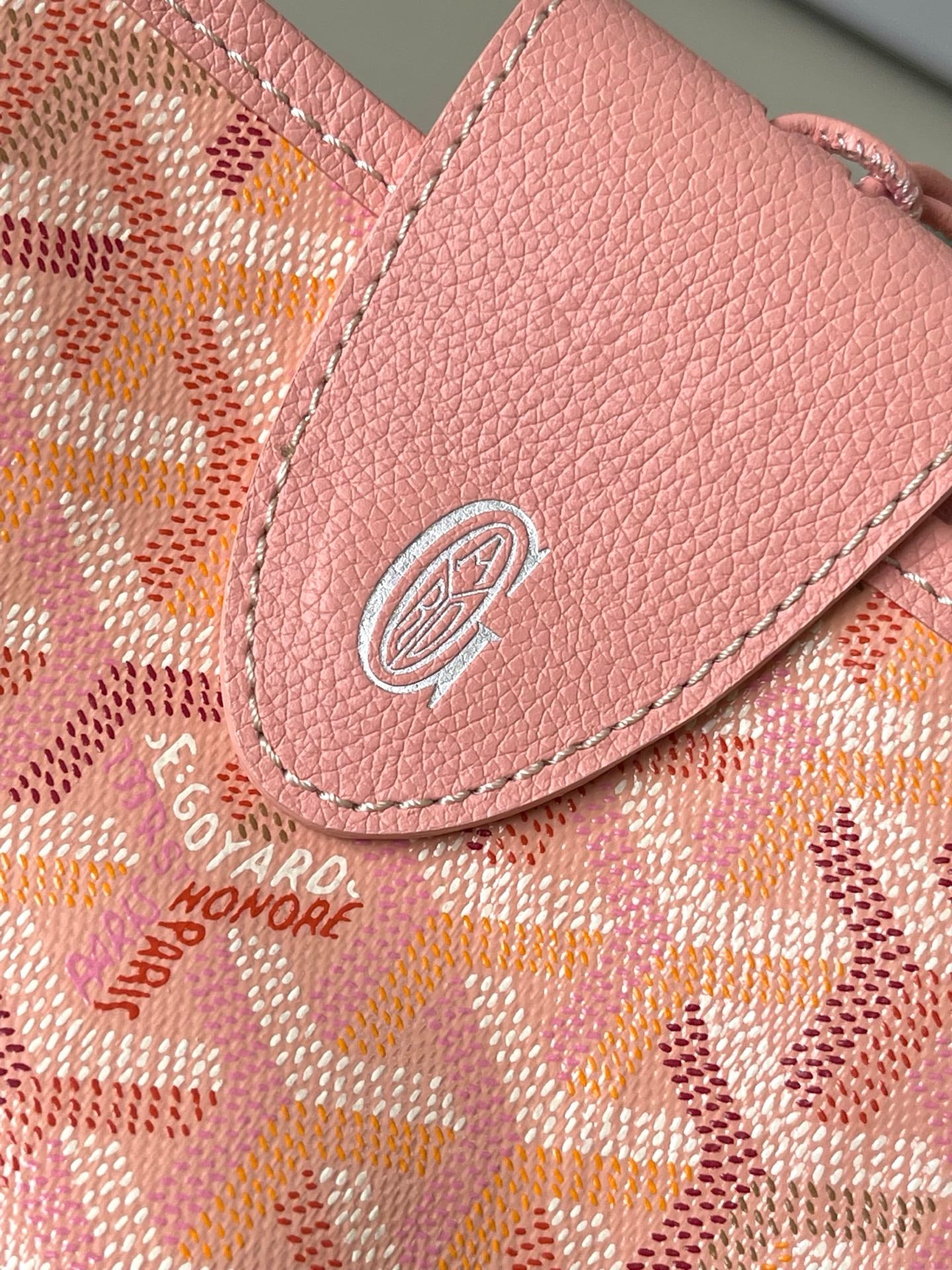 Pink leather trim and embossed logo on patterned tote bag front flap