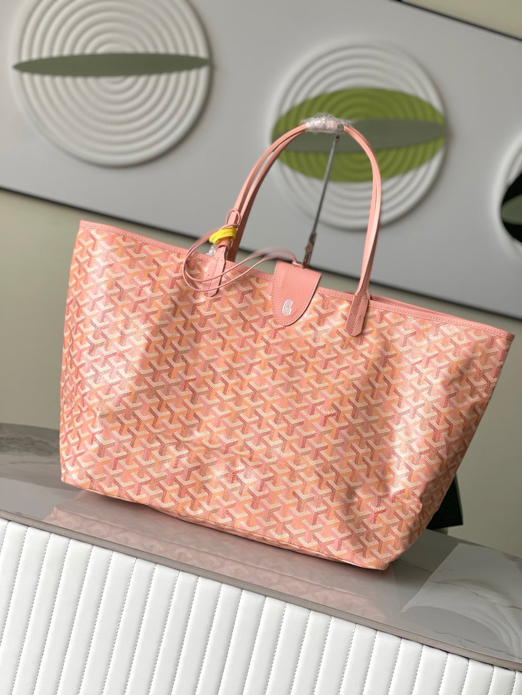 Pink patterned tote bag angled view with top handles and front emblem