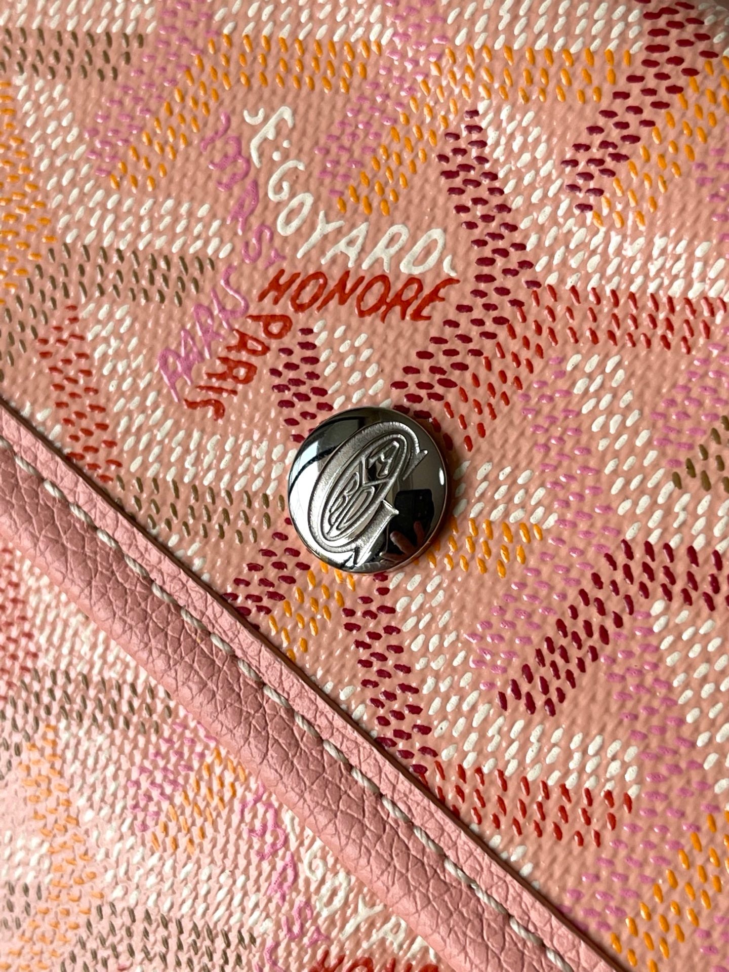 Logo hardware button on patterned pink tote bag with textured trim