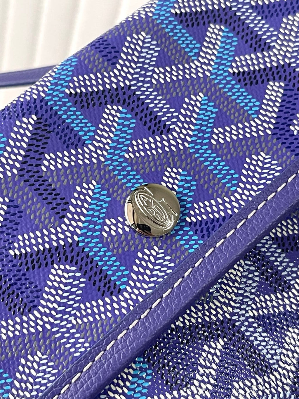 Blue patterned Goyard wallet with snap button and purple leather edging