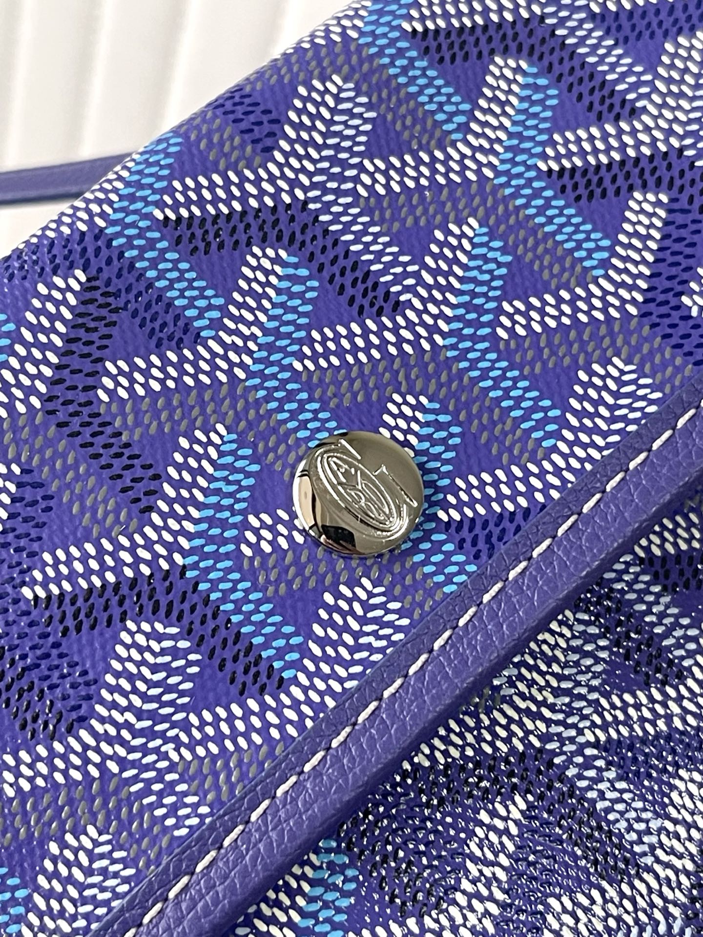 Blue patterned Goyard wallet with snap button and purple leather edging