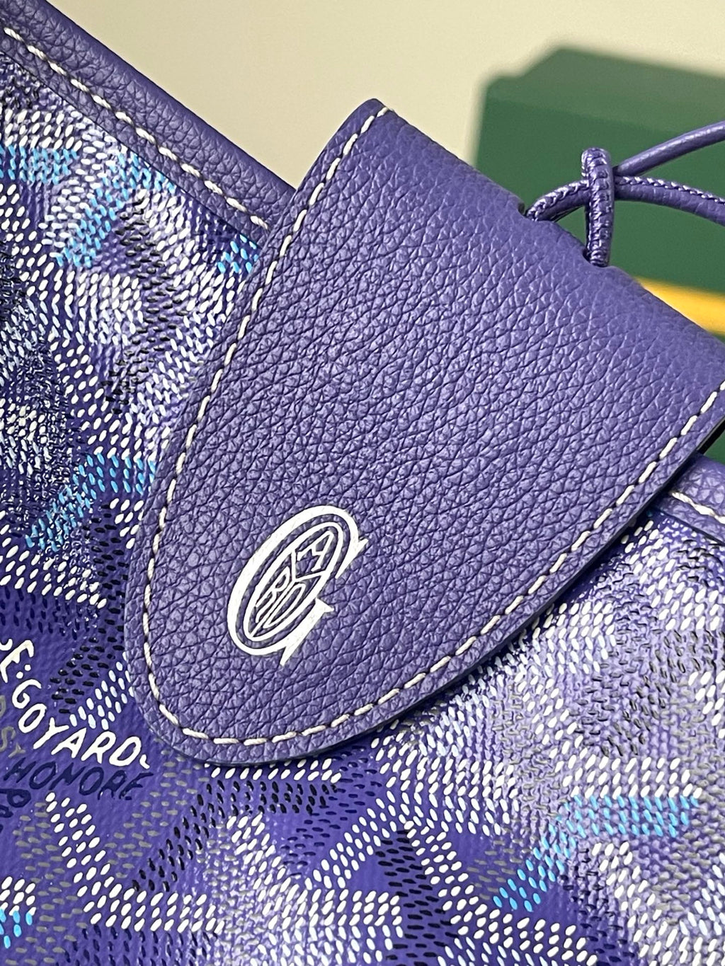 Purple leather trim detail with round logo patch on blue patterned bag