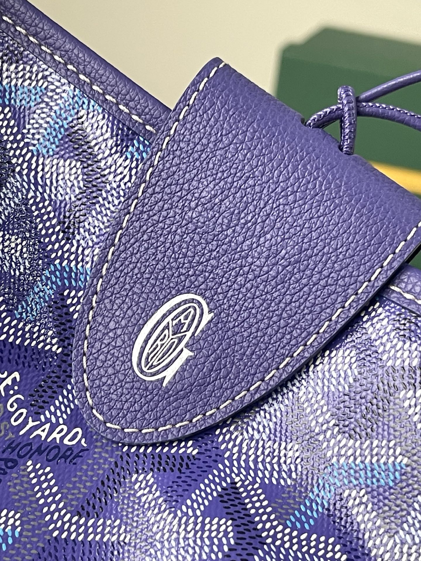 Purple leather trim detail with round logo patch on blue patterned bag