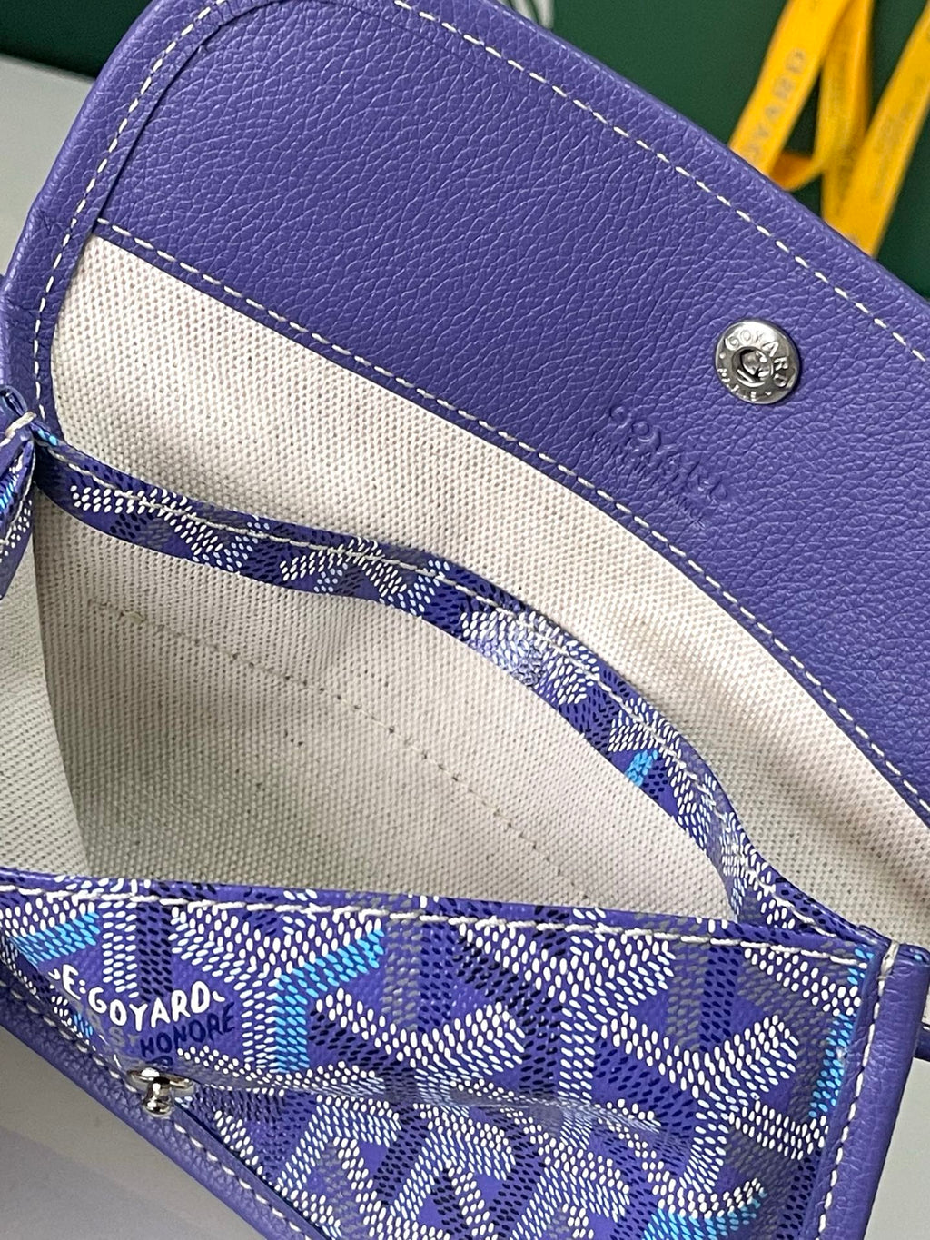 Blue patterned Goyard mini pouch with beige lining and snap closure